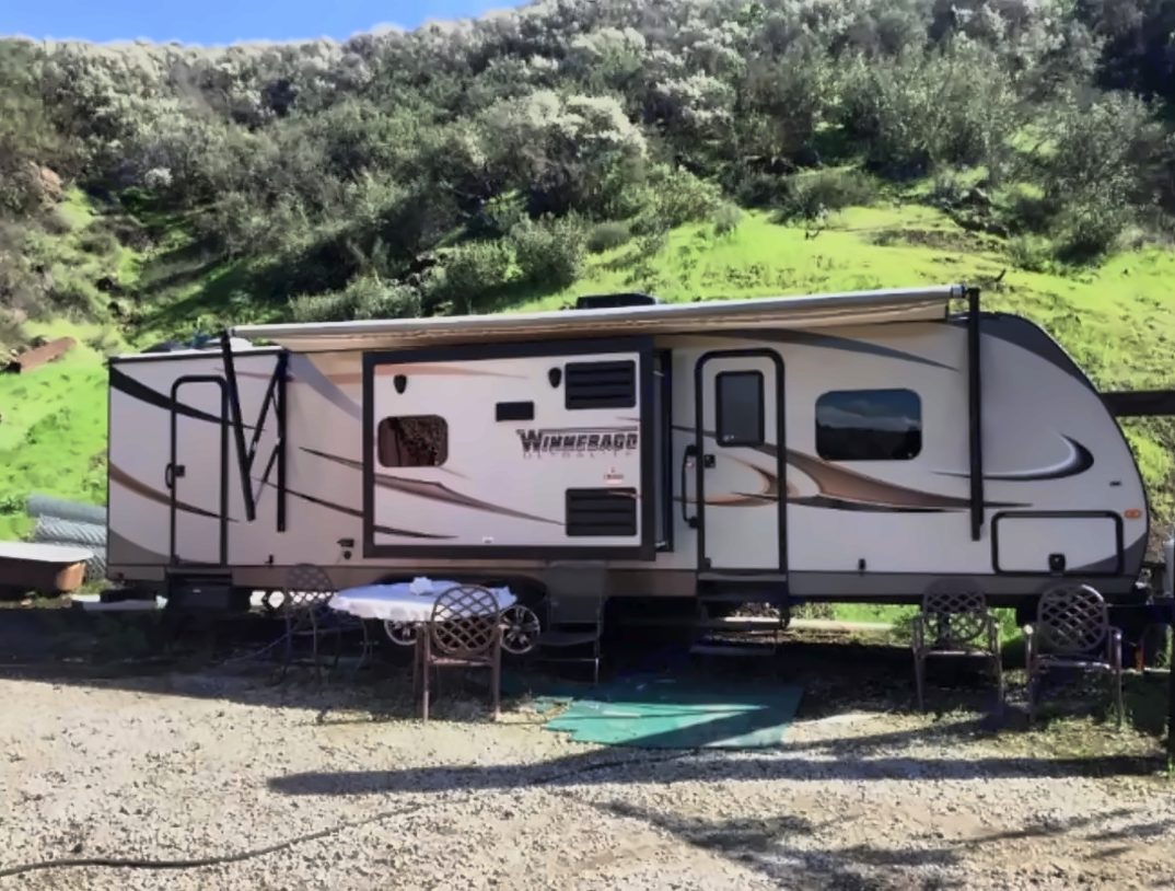 Trailer set up at a campsite with outdoor table and chairs