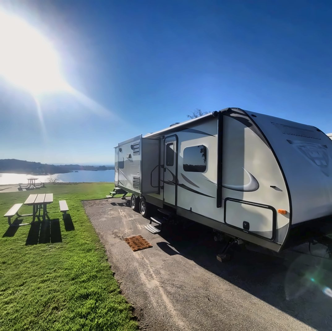 Our Winnebago Ultralite travel trailer set up at a lakeside campsite